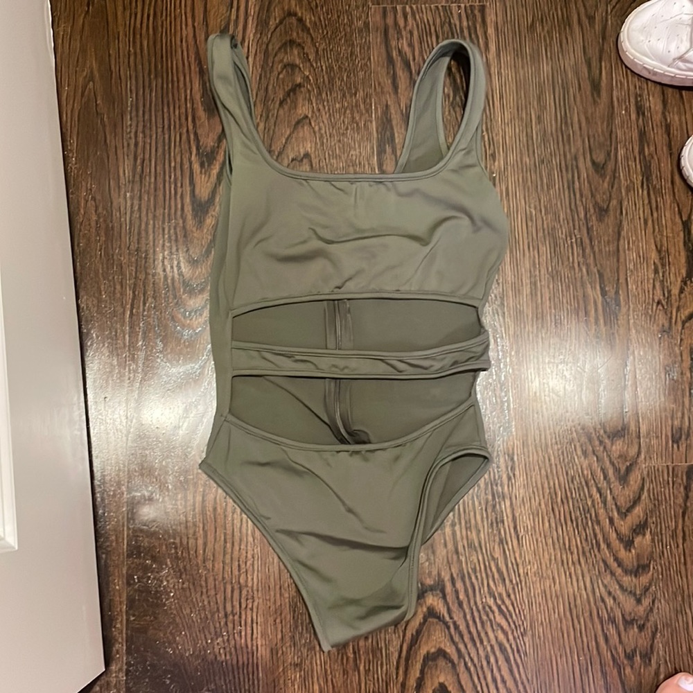 Army green body suit with cut outs in the middle. Zip up closure.